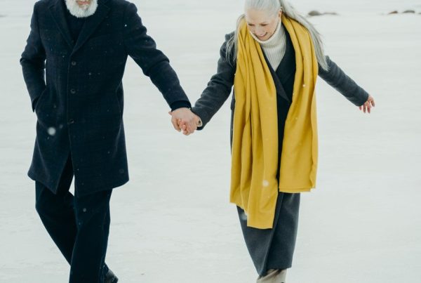 Couple de seniors actifs marchant main dans la main, accompagnés par les ostéopathes Ostéovale